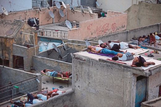 PENDUDUK di New Delhi tidur di bumbung bangunan kerana kepanasan,  semalam. 