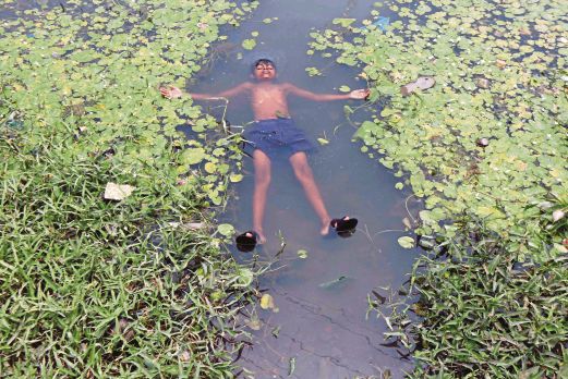  SEORANG budak lelaki berenang di sebuah tasik di Kolkata untuk menyejukkan badannya.