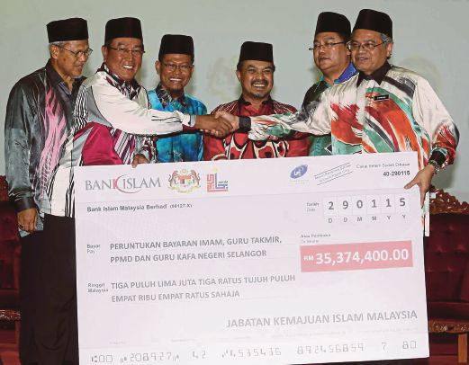 KETUA Pengarah JAKIM Datuk Othman Mustapha (kanan) menyerahkan replika cek RM35 juta kepada Pengarah Jabatan Agama Islam Selangor Datuk Haris Kassim sambil diperhatikan Jamil Khir (tiga dari kanan).