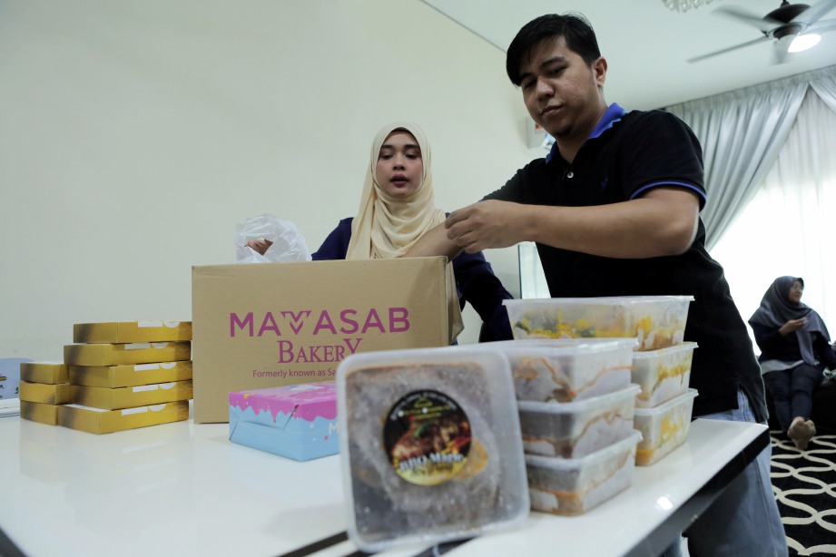 NURSYAMIMI dibantu suaminya, Ahmad Syahir Tobri, 33, menyusun produk yang ditempah sebelum membuat penghantaran secara pos kepada pelanggan.