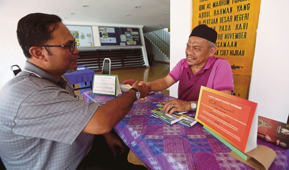 AMIL zakat fitrah,  Zaher Rudin Moktar (kanan) menerima akad bayaran zakat fitrah di Masjid Negeri, Seremban. 