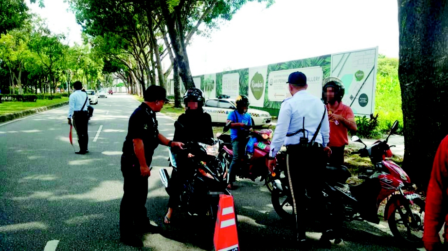 ANGGOTA polis trafik melakukan pemeriksaan terhadap penunggang motosikal di pekarangan SMK Seri Permaisuri, Cheras, Kuala Lumpur.