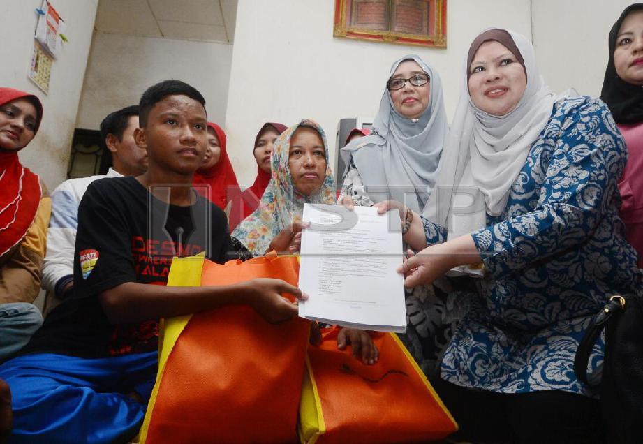 RINA (kanan) menyerahkan surat tawaran kemasukan ke MRSM kepada Muhammad Aiman. FOTO Shahnaz Fazlie Shahrizal