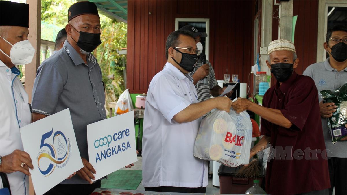 ABDUL Fattah (tengah) menyerahkan keperluan barangan asas kepada mangsa banjir. FOTO Mohd Amin Jalil