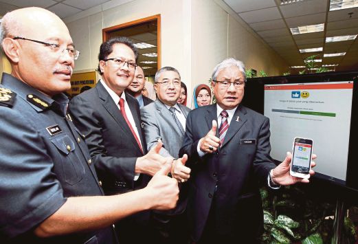 HASAN (kanan) menunjukkan aplikasi MyKira GST pada telefon pintar selepas merasmikan aplikasi berkenaan pada Majlis Perasmian Bilik Gerakan Anti Pencatutan dan aplikasi MyKira GST di KPDNKK, Putrajaya.