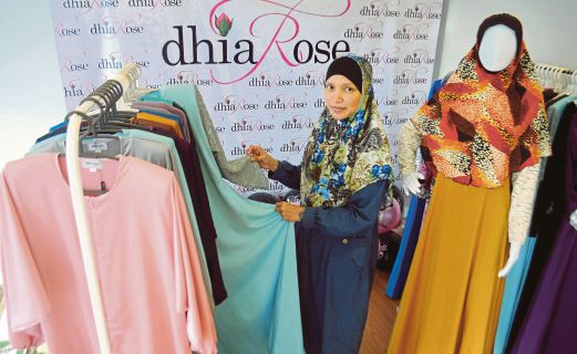 ROSMAWATI menunjukkan pakaian wanita muslimah yang dijual di butiknya. 