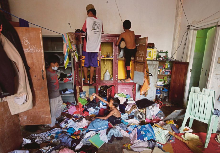 PENDUDUK membersihkan kediaman mereka yang berselerak selepas pulang dari pusat pemindahan sementara. - Reuters