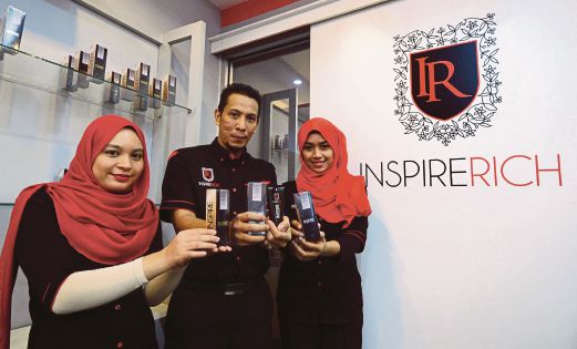 Izwandi (tengah) bersama kakitangannya menunjukkan Perfumed Deep Heat Lotion Inspire yang dijual atas talian.