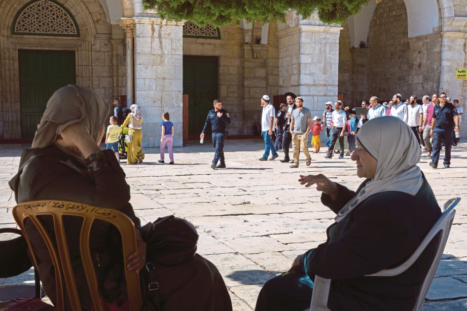WANITA Palestin duduk berhampiran Masjid Al-Aqsa ketika polis Israel mengiringi penduduk Yahudi melawat pekarangan masjid berkenaan,  semalam.  - EPA 