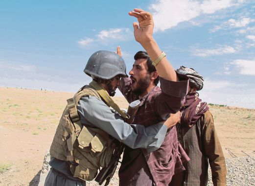 SEORANG anggota tentera Afghanistan memeriksa seorang lelaki di Helmand, semalam.