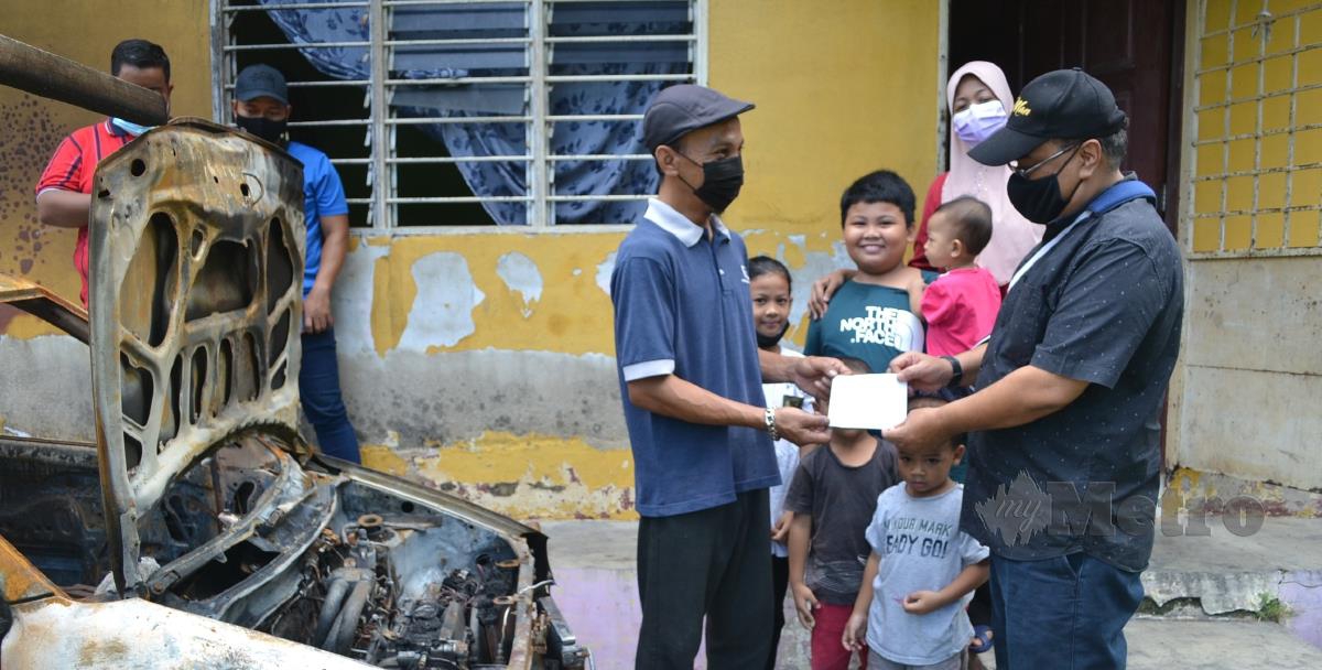 Shahrul Nizam (tengah) menerima sumbangan wang tunai daripada Nor Azman di Kampung Pantai Rombang, Tanjung Kling. FOTO HASSAN OMAR