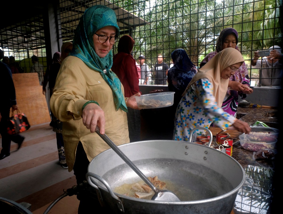 TUNKU Azizah berkenan memasak untuk mangsa banjir DI PPS Kampung Chedong, Maran hari ini. FOTO Bernama.