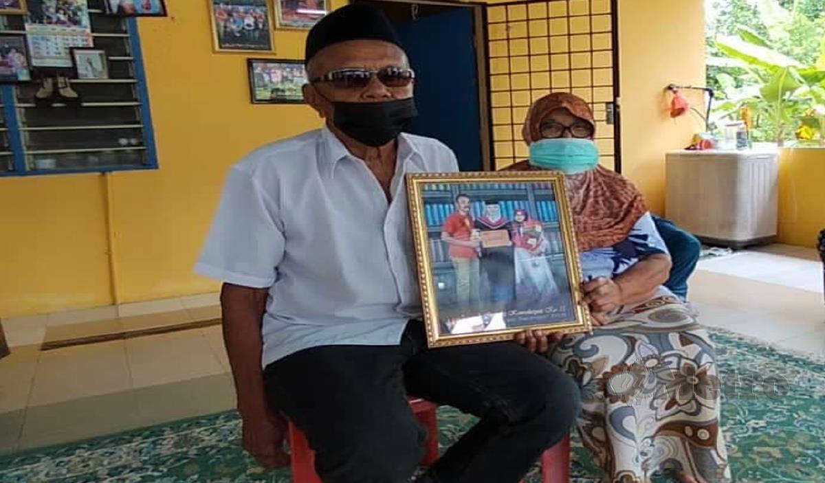 SITI Rudiah dan suaminya, Misnon Sidek memegang gambar arwah Nazli (baju merah) yang meninggal dunia dalam kemalangan semalam. FOTO Amirul Aiman Hamsuddin. 