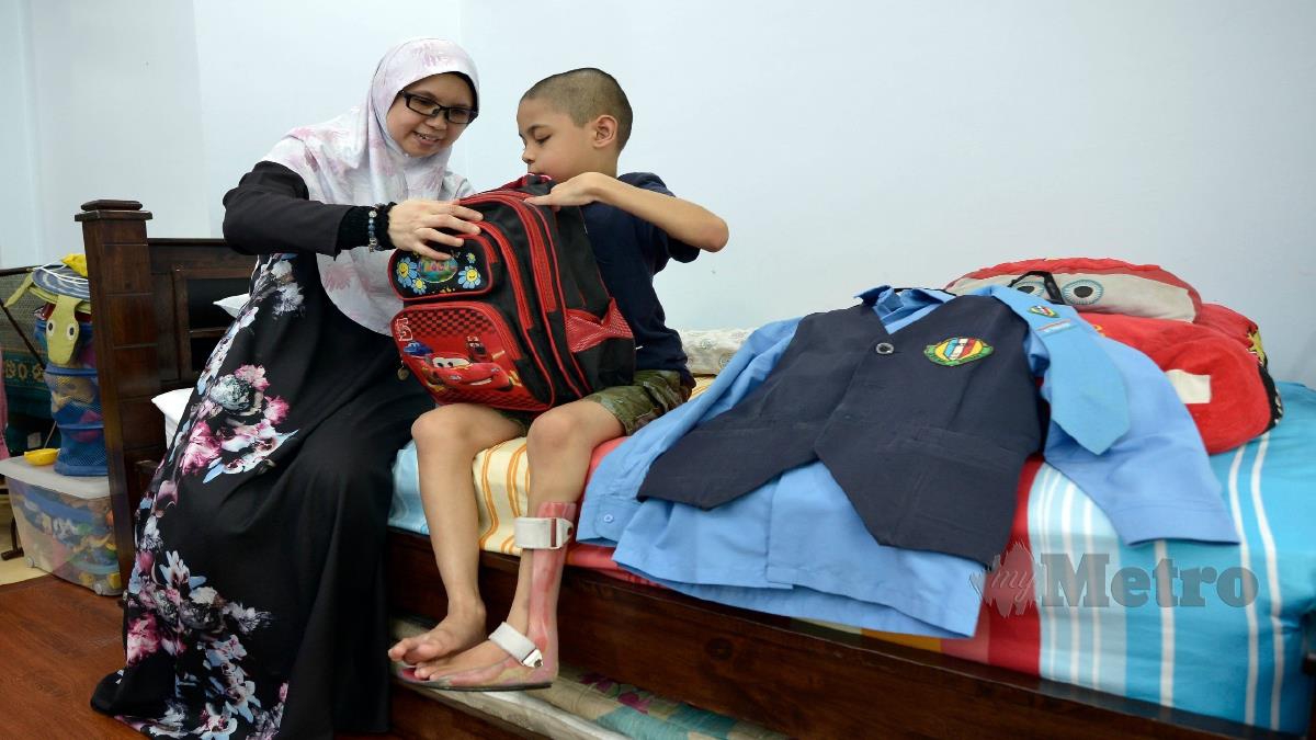 MAZDIANA Makmor membantu Muhammad Aqma Azizul melakukan persiapan untuk masuk sekolah yang akan bermula esok. FOTO AIZUDDIN SAAD