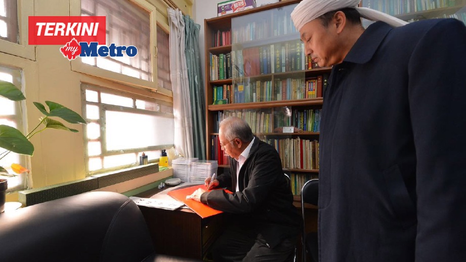 NAJIB menandatangani buku tetamu disaksikan Imam Masjid Dongzhimen di Beijing.