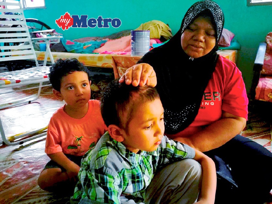 SALMAH (kanan) menunjukkan kesan pembedahan membuang tempurung kepala  Akmal selepas  dilanggar sebuah motosikal ketika ditemui di rumahnya di Kuala Triang. FOTO/SHAHRINNAHAR LATIB