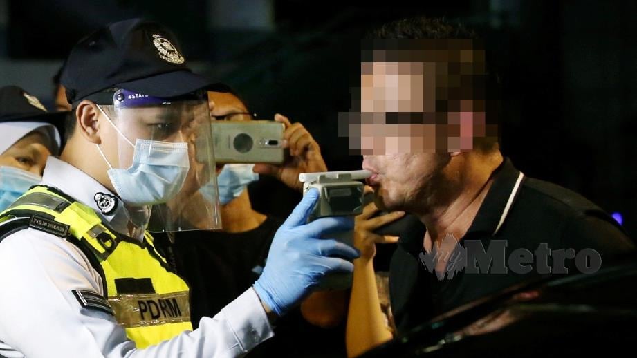 ANGGOTA PDRM melakukan ujian pengesanan alkohol dalam badan terhadap pemandu menggunakan alat pengesan kandungan alkohol di sekatan jalan raya yang dilaksanakan bagi mengesan pemandu mabuk di Jalan Hang Tuah, Kuala Lumpur, semalam. FOTO Eizairi Shamsudin