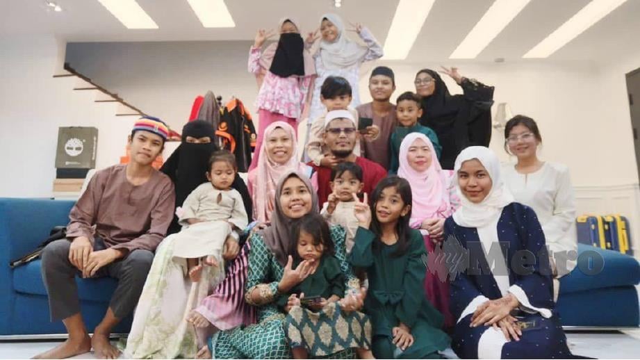 MOHD Fazil (duduk tengah, berbaju merah) dari Kampung Pandan bersama empat isteri dan 14 anak ceria beraya bersama. FOTO Ihsan keluarga Mohd Fazil