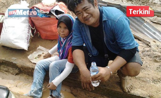 KANAK-KANAK mangsa banjir di Kampung Major, Kuala Krai, menikmati nasi bungkus sambil ditemani seorang peserta misi bantuan, Mohd Nizam Omar, 40. FOTO ihsan Seri Ziyanti Sufiantan