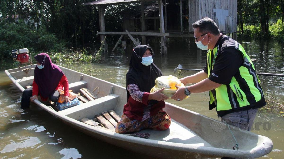 JOHAN Ariff (kanan) menyampaikan sumbangan keperluan makanan kepada penduduk yang terjejas banjir. FOTO Nik Abdullah Nik Omar