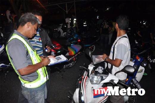 ANGGOTA polis memeriksa dokumen penunggang motosikal yang ditahan.