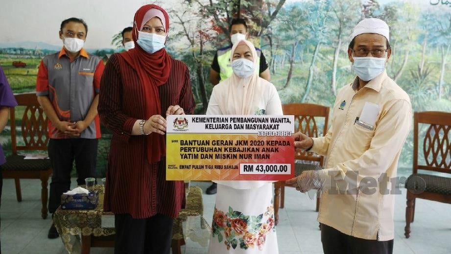 RINA (kiri) menyerahkan replika cek kepada Yang Dipertua Pertubuhan Kebajikan Anak Yatim dan Miskin Nur Iman, Badrul Huzaini Mohd Yusof (kanan) sambil diperhatikan Shahaniza (tengah). FOTO Farizul Hafiz Awang 