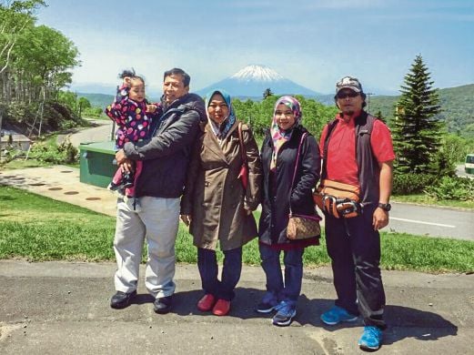WAN Ab Aziz (kanan) bergambar bersama pelancong dari Malaysia dengan berlatar belakangkan Gunung Yotei.