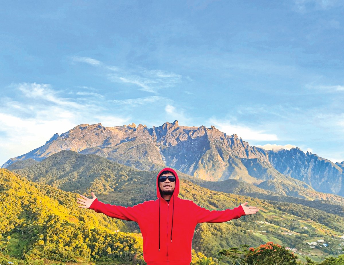BERGAMBAR berlatarkan Gunung Kinabalu.