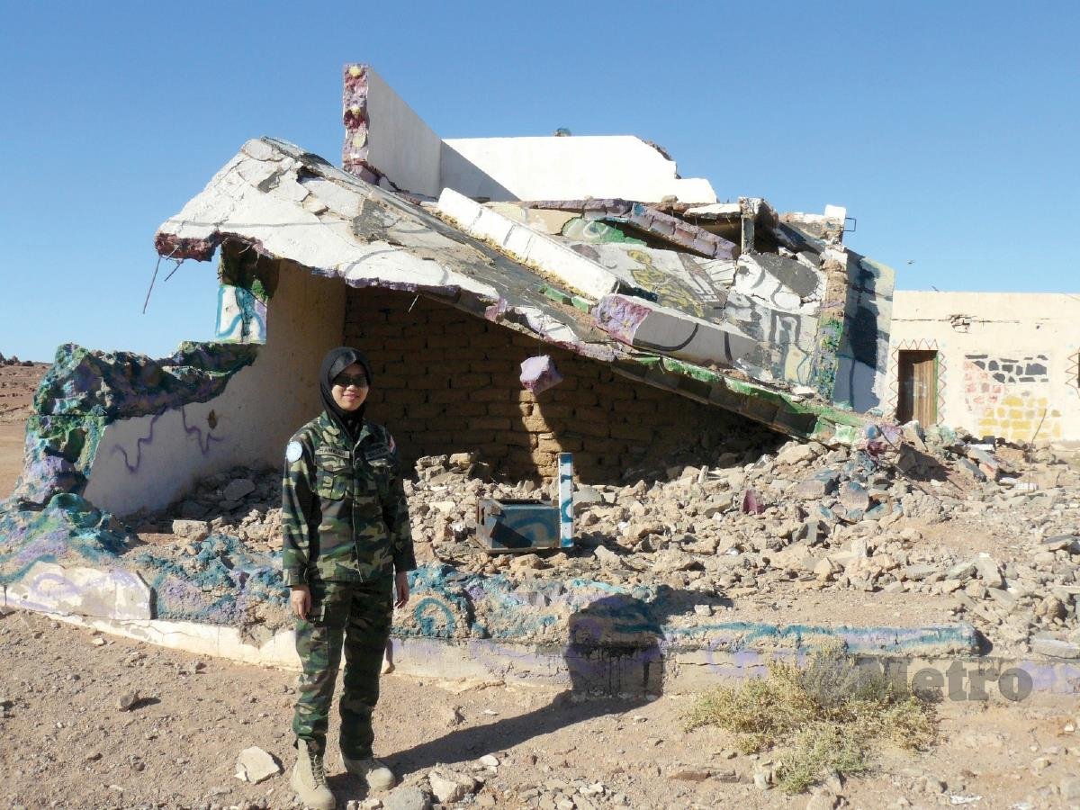 DR Hamidah di depan kesan bangunan dibom dalam perang di Sahara Barat.