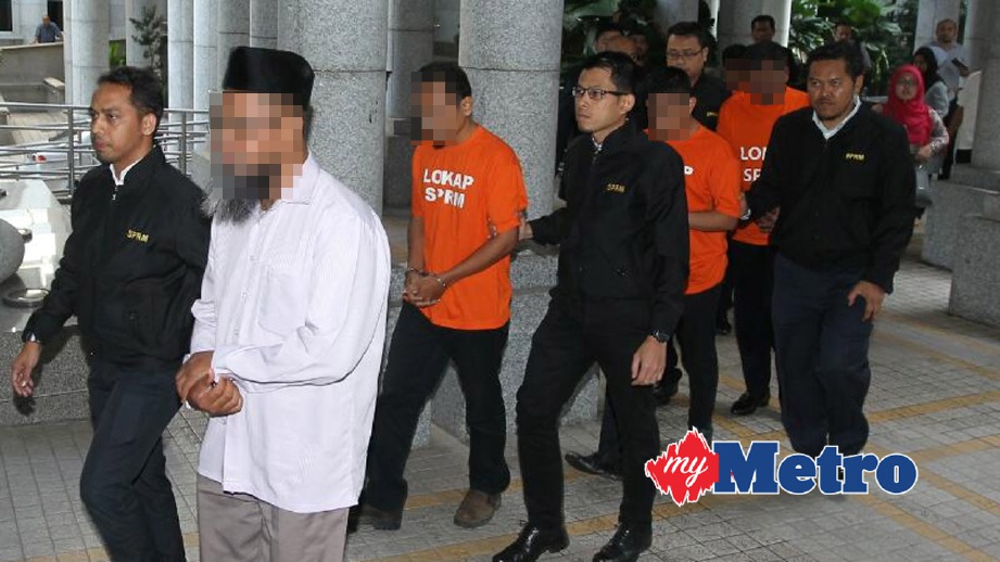 PEGAWAI SPRM membawa suspek ke Mahkamah Majistret Putrajaya. FOTO Ahmad Irham Mohd Noor