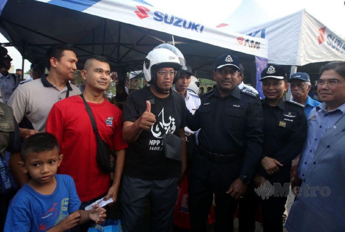 HUSSEIN Omar (empat, kanan) menyampaikan topi keledar kepada penunggang motosikal ketika Majlis Kempen Keselamatan Jalan Raya sempena Hari Raya Aidilfitri 2024 hari ini. FOTO Hairul Anuar Rahim.