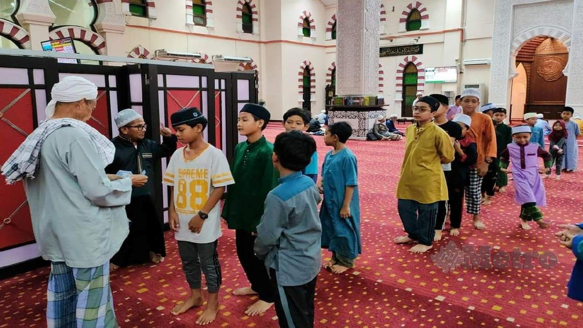 AHLI jawatan kuasa Masjid Hadhari mengagihkan wang insentif buat kanak-kanak yang hadir untuk solat jemaah. FOTO Nurul Fatihah Sulaini.
