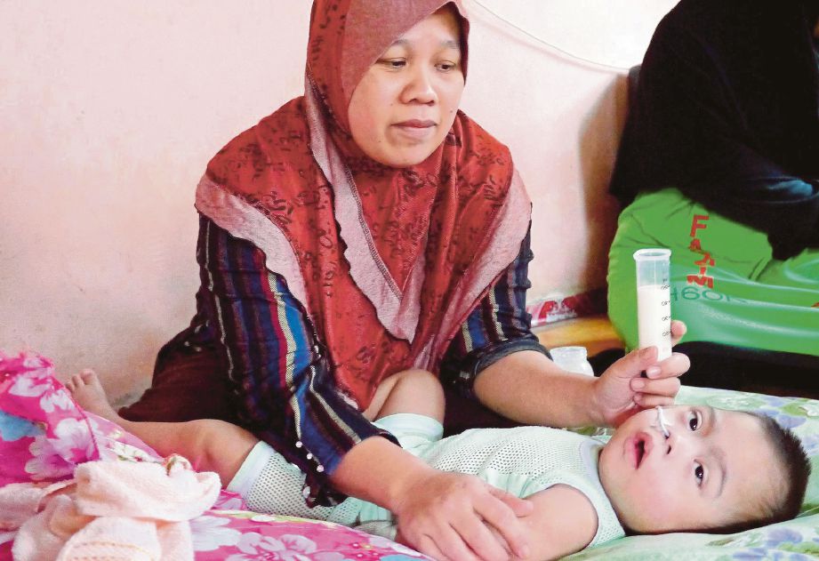  Zurina  memberi susu khas kepada anaknya,  Muhammad Amar Firdaus  di Bukit Goh. 