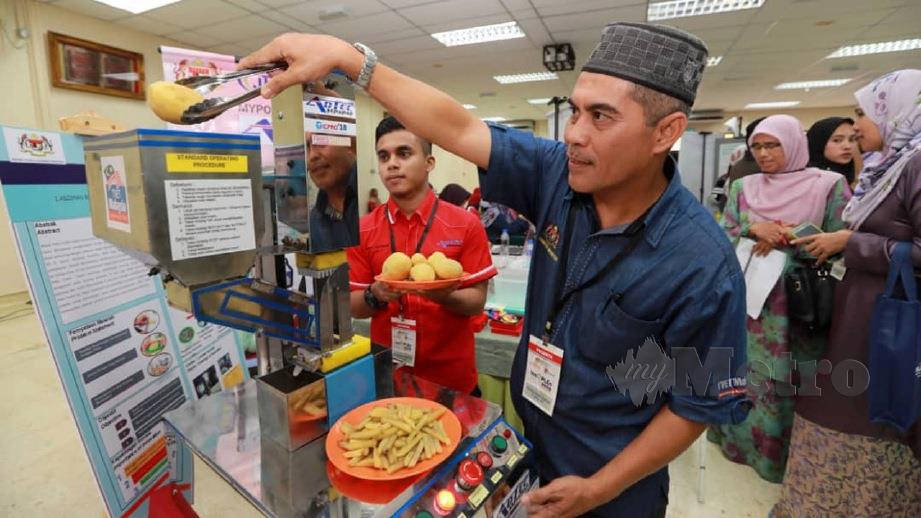ASZIMAN (kanan) bersama penuntut, Mohd Asyraaf Asziman mempamerkan mesin memotong kentang ketika Program INNOPLEN 2019 peringkat Kebangsaan. FOTO Mohd Rafi Mamat
