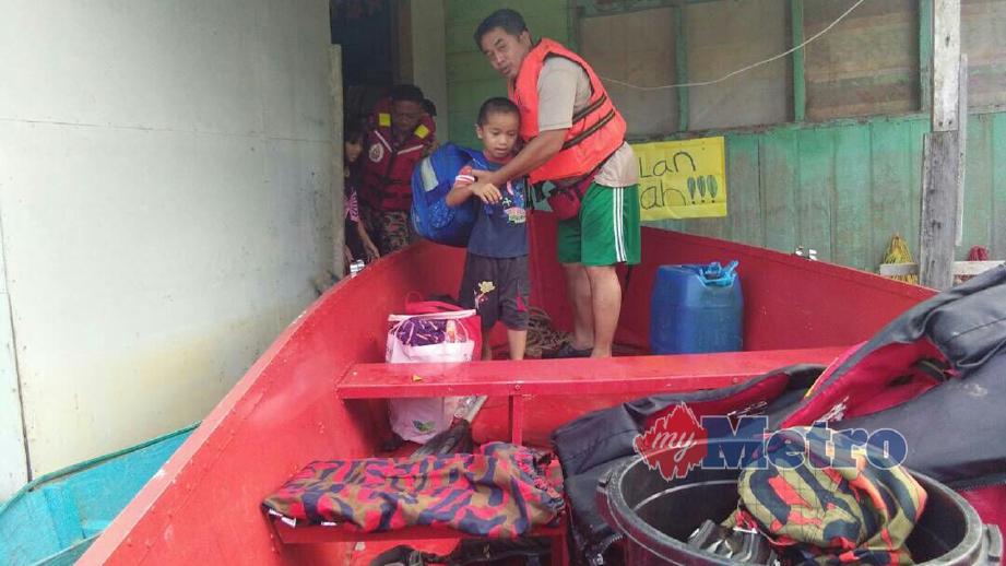 ANGGOTA bomba memindahkan penduduk terjejas banjir di Limbang. FOTO ihsan Bomba