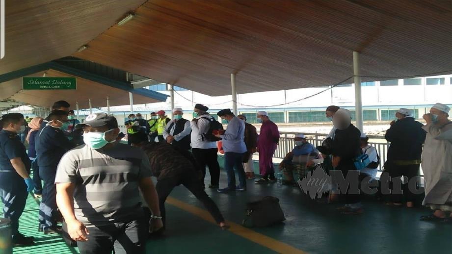 JEMAAH tabligh diiring pihak berkuasa sebaik tiba di Terminal Feri Tawau sebelum diserahkan kepada MKN. FOTO Ihsan pembaca.