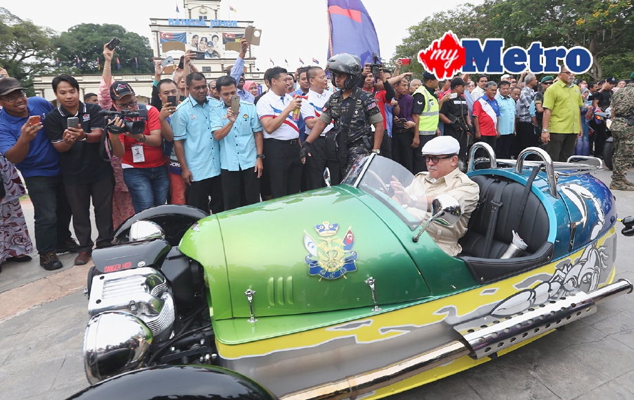 SULTAN Johor, Sultan Ibrahim memandu kereta beroda tiga Morgan ketika majlis Pelepasan Kembara Mahkota Johor 2017 oleh Yang DiPertua Majlis Perbandaran Muar, Jamaludin A. Hamid (tujuh dari kiri) di Dataran Tanjung Emas. FOTO Adi Safri