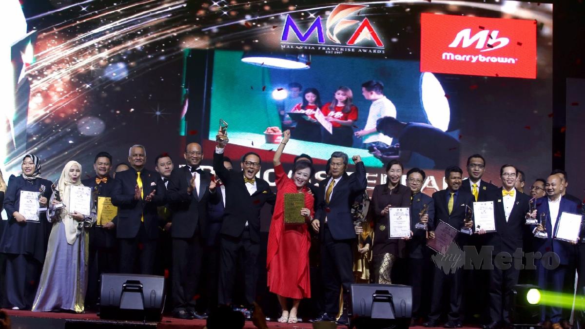 Azman (lima dari kiri) menyampaikan anugerah Francais Terbaik kepada Pengasas dan Pengarah Urusan Kumpulan MarryBrown Sdn Bhd, Datin Nancy Liew sambil diperhatikan Dr Radzali pada Majlis Malam Anugerah Francais Malaysia 2022 hari ini. FOTO Hairul Anuar Rahim.
