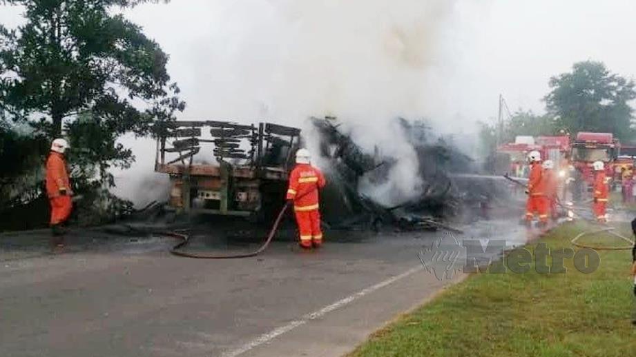 ANGGOTA bomba memadam kebakaran treler dan lori yang terbabit kemalangan. FOTO Rosli Ilham