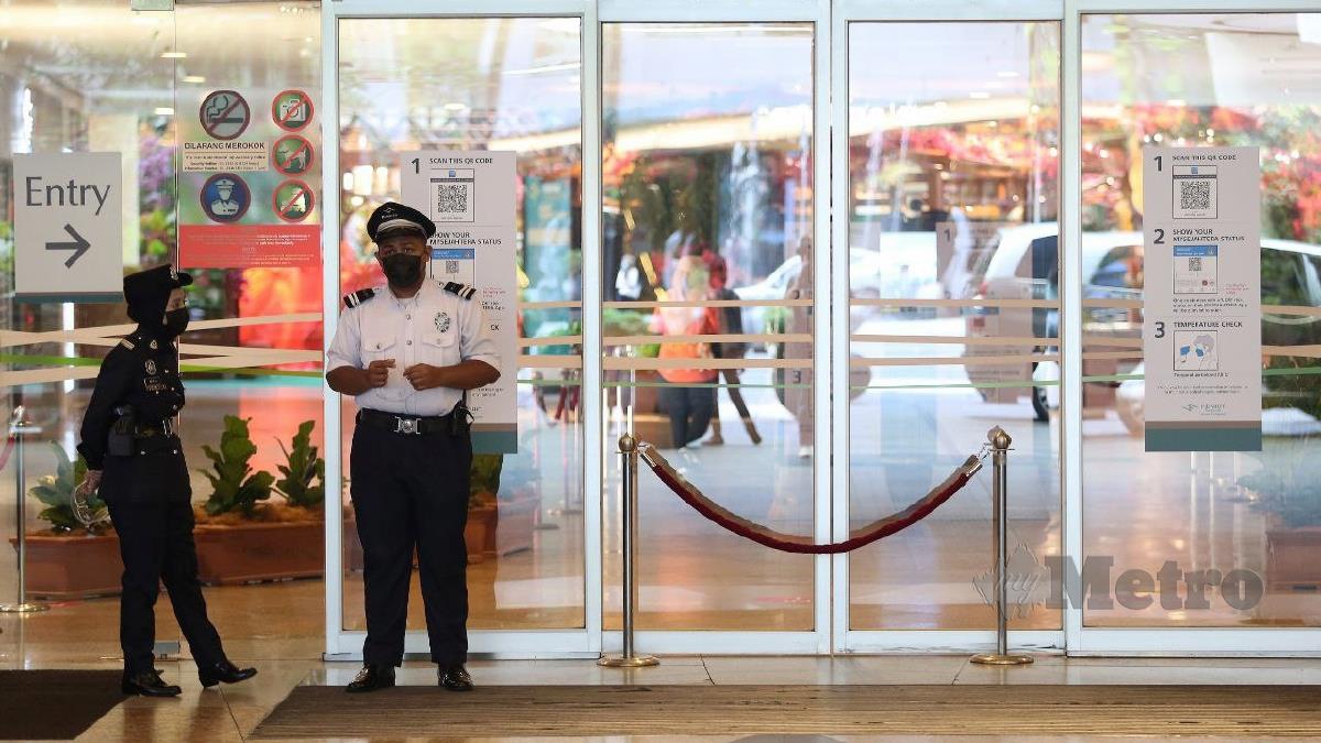 PENGAWAL keselamatan dan anggota Polis Bantuan mengawal pintu masuk pusat beli belah di Kuala Lumpur, kelmarin. FOTO Hazreen Mohamad