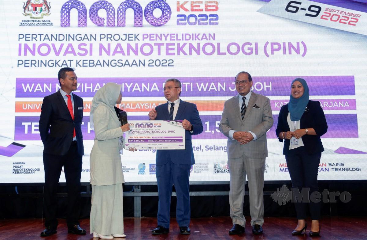 DR Adham menyampaikan hadiah kepada pemenang tempat pertama Pertandingan Projek Penyelidikan Inovasi Nano Teknologi Peringkat Kebangsaan 2022, Wan Nazihah Liyana Wan Jusoh. FOTO Aizuddin Saad.