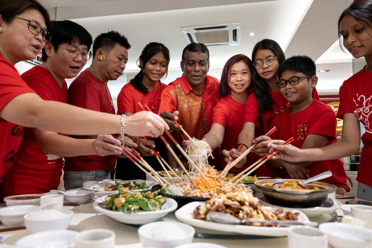 MANIMARAN (tengah) menggaul Yee Sang bersama isterinya Ooi (empat, kanan) dan keluarganya ketika sambutan Tahun Baru Cina di sebuah restoran di Ipoh. FOTO Bernama.