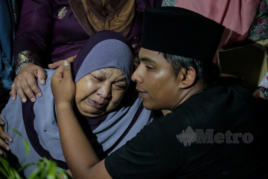 ADIK kepada Abam Bocey, Syed Ali Mubarak Syed Mohd Ridzuan menenangkan ibunya, Sabariah Arshad selepas jenazah selamat dibumikan Tanah Perkuburan Islam Jalan Sungai Pusu. FOTO Asyraf Hamzah