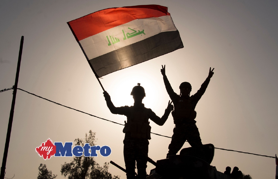 ANGGOTA polis Iraq mengibarkan bendera negara ketika meraikan kemenangan di Mosul. FOTO AFP