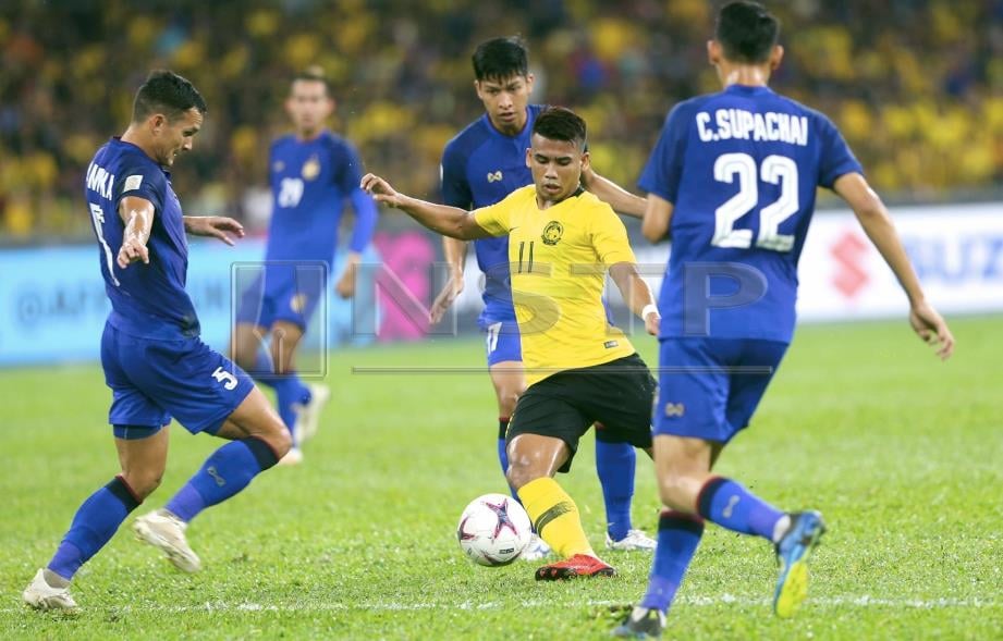 PEMAIN Malaysia, Muhamad Safawi Rasid (tengah) cuba dihalang pemain Thailand pada aksi separuh akhir pertama Piala Suzuki AFF di Stadium Bukit Jalil. FOTO Mohamad Shahril Badri Saali