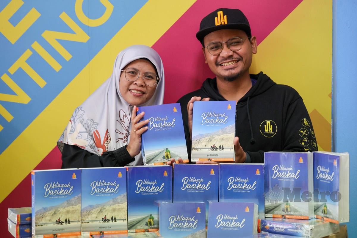 AHMAD bersama isteri Noradilah menunjukkan hasil karya mereka dalam novel travelog bersiri berjudul, Ustazah Basikal - Nekad ke Makkah dan Ustazah Basikal - Yakin Kerana Dia. FOTO Bernama