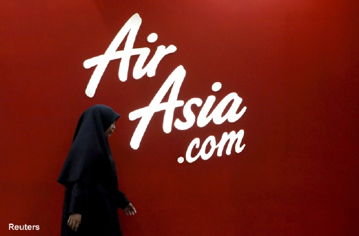 A woman walks past the AirAsia logo at its sales centre in Kuala Lumpur, Malaysia, in this June 17, 2015 file photo. Founders of Asia's No.1 budget carrier AirAsia Bhd are sounding out investors to take the company private in a management-led buyout, after its shares took a beating this year following a critical research report, people familiar with the matter said. AirAsia boss Tony Fernandes and his long-time business partner Kamarudin Meranun are working with banks to secure financing for the transaction, which could be launched over the next few months, said the people, who did not want to be identified as the discussions are confidential. An AirAsia spokeswoman had no immediate comment when contacted by Reuters. To match Exclusive AIRASIA-MANAGEMENT/   REUTERS/Olivia Harris/Files