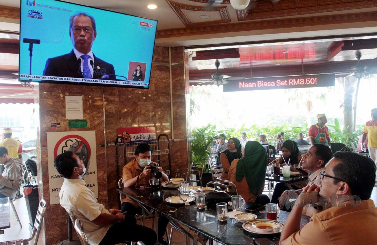 ORANG ramai yang sedang menjamu selera di sebuah restoran menonton Amanat Perdana Setahun Malaysia Prihatin secara langsung melalui televisyen di Taman Adda, Johor Bahru. FOTO Zain Ahmed.