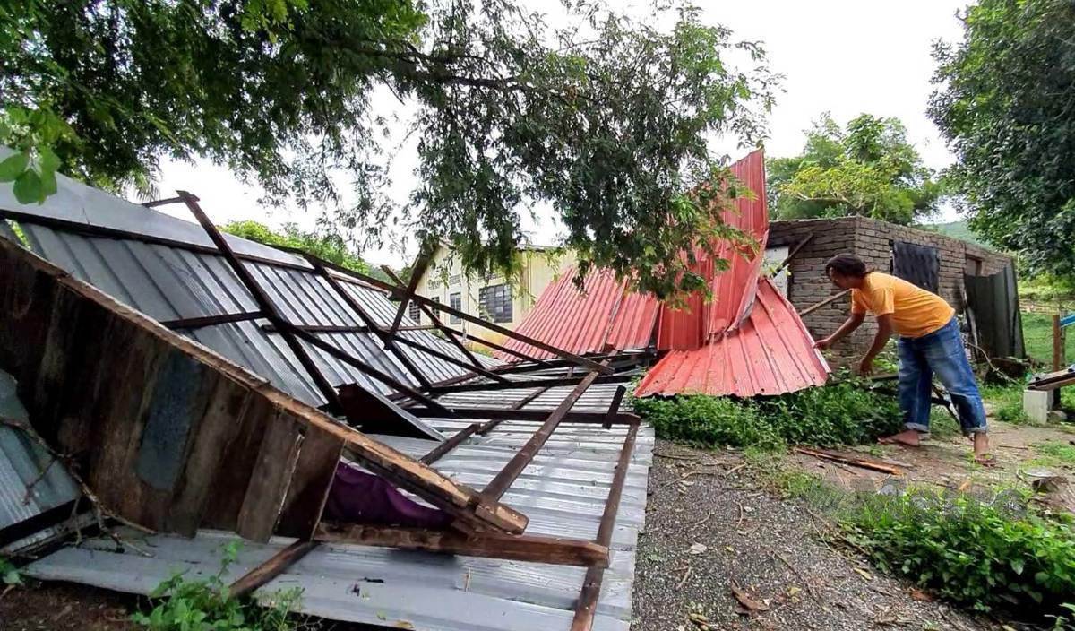 RIDZWAN menunjukkan bumbung dapur rumahnya yang diterbangkan angin dalam kejadian ribut di Kampung Yooi, Langkawi. FOTO Hamzah Osman