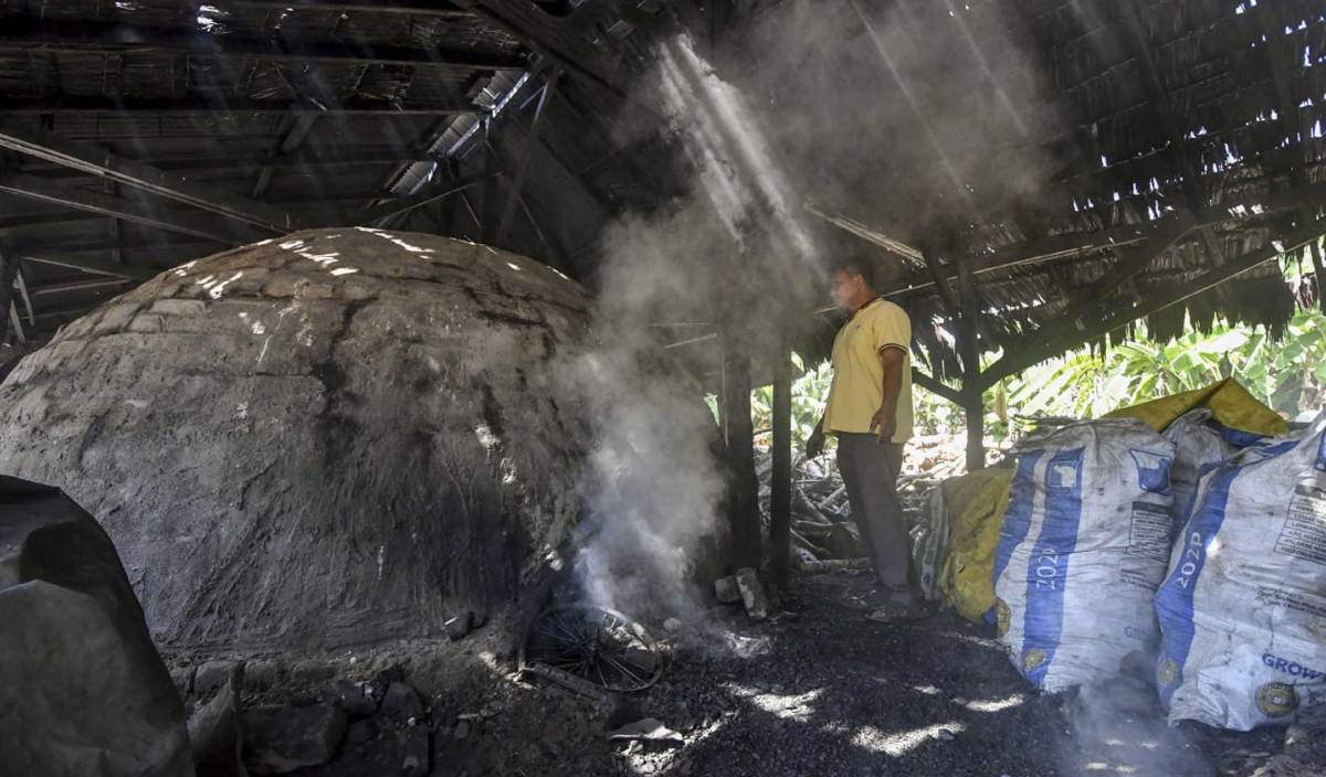 NAZRI memantau proses membakar kayu  dalam ‘gok’ untuk dijadikan arang di Kampung Bukit Mak Lipah, Mahligai, Bachok. FOTO BERNAMA
